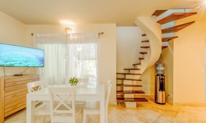 Uma sala de estar moderna com área de jantar, televisão de tela plana, escada e bebedouro.
