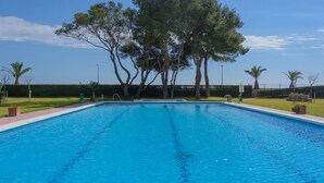 Ein rechteckiger Swimmingpool mit klarem, blauem Wasser, umgeben von einer niedrigen Hecke und mehreren Bäumen.