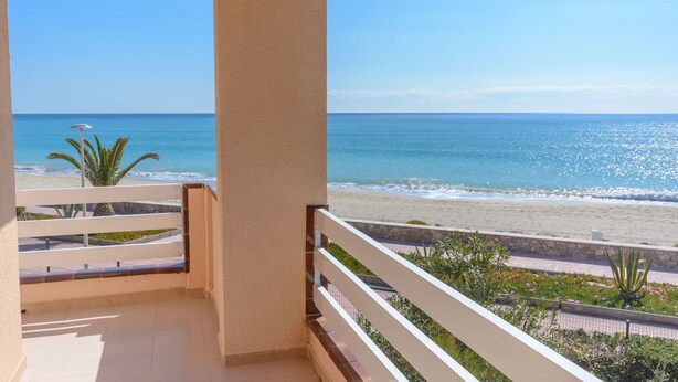 Ein Balkon mit Blick auf Strand und Meer.