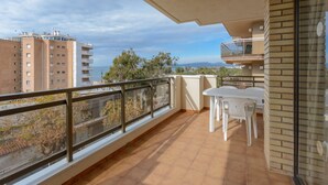 Ein Balkon mit Blick auf Gebäude und Bäume, ausgestattet mit einem Tisch, Stühlen und einem Glasgeländer.