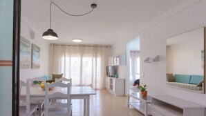 En moderne stue med spiseplads, et fjernsyn og et stort spejl.