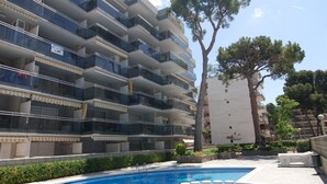 A modern multi-story building with balconies, a swimming pool, and surrounding greenery. - Montblanc Basic Zeus Salou 01521 (Salou)