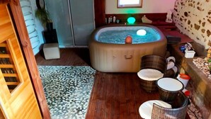 Uma área de spa com hidromassagem, cadeiras de vime e parede de pedra.
