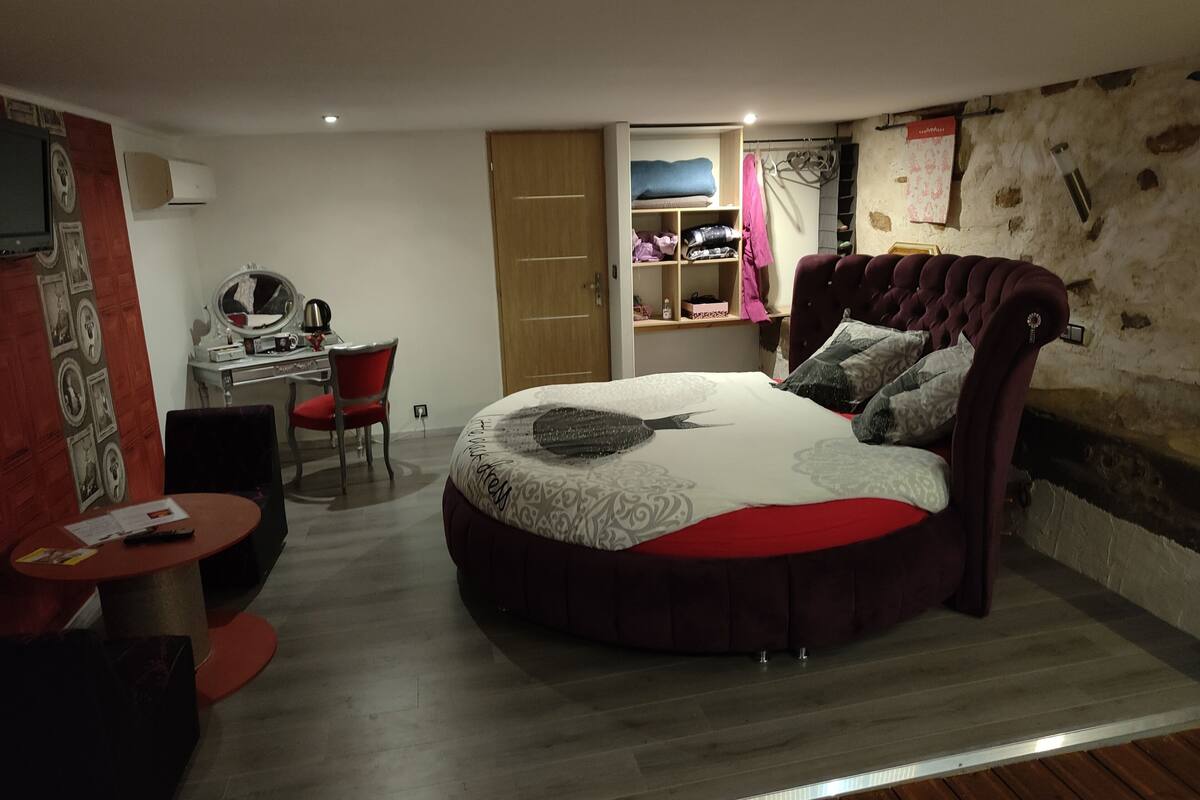 Un dormitorio con una cama redonda, un escritorio y una silla.