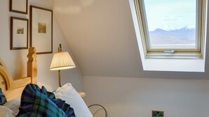 A bedroom with a sloped ceiling, a bed with a plaid blanket, a bedside lamp, and framed pictures on the wall. - 1 bedroom accommodation in Fearnmore, near Applecross (Fearnmore, near Applecross)