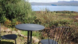 An outdoor seating area with a table and chairs overlooking a lake and distant mountains. - 1 bedroom accommodation in Fearnmore, near Applecross (Fearnmore, near Applecross)