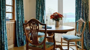 A dining area with a round table, four wooden chairs, and a vase of flowers. - 1 bedroom accommodation in Fearnmore, near Applecross (Fearnmore, near Applecross)