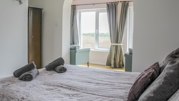 Une chambre à coucher avec un lit, une télévision, une fenêtre avec des rideaux et une vue sur l’extérieur.