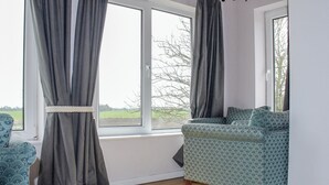 Une pièce avec un canapé, une fenêtre avec des rideaux et une vue sur l’extérieur.