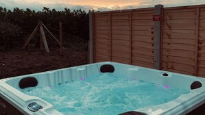 Un bain à remous avec jets, entouré d’une clôture en bois, et un panneau interdisant de fumer ou d’utiliser des objets en verre.