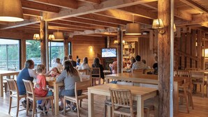 Un interior de madera con mesas, sillas, un televisor y una estantería.
