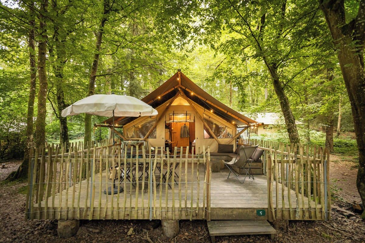 Una cabaña de madera con terraza, rodeada de árboles.