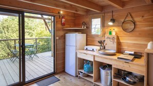 Cocina pequeña con refrigerador, lavamanos y estantes de madera.