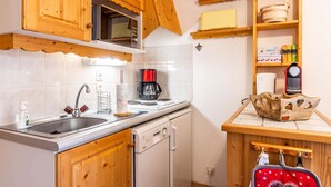 A compact kitchen with wooden cabinets, a microwave, a coffee maker, and a dishwasher. - Lovely apartment at the bottom of the slopes (MORZINE)