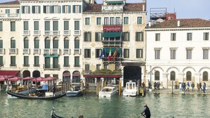 A canal with gondolas and boats, historic buildings with balconies, and a sign indicating a restaurant. - EGO’ Boutique Hotel - The Silk Road (Venice)
