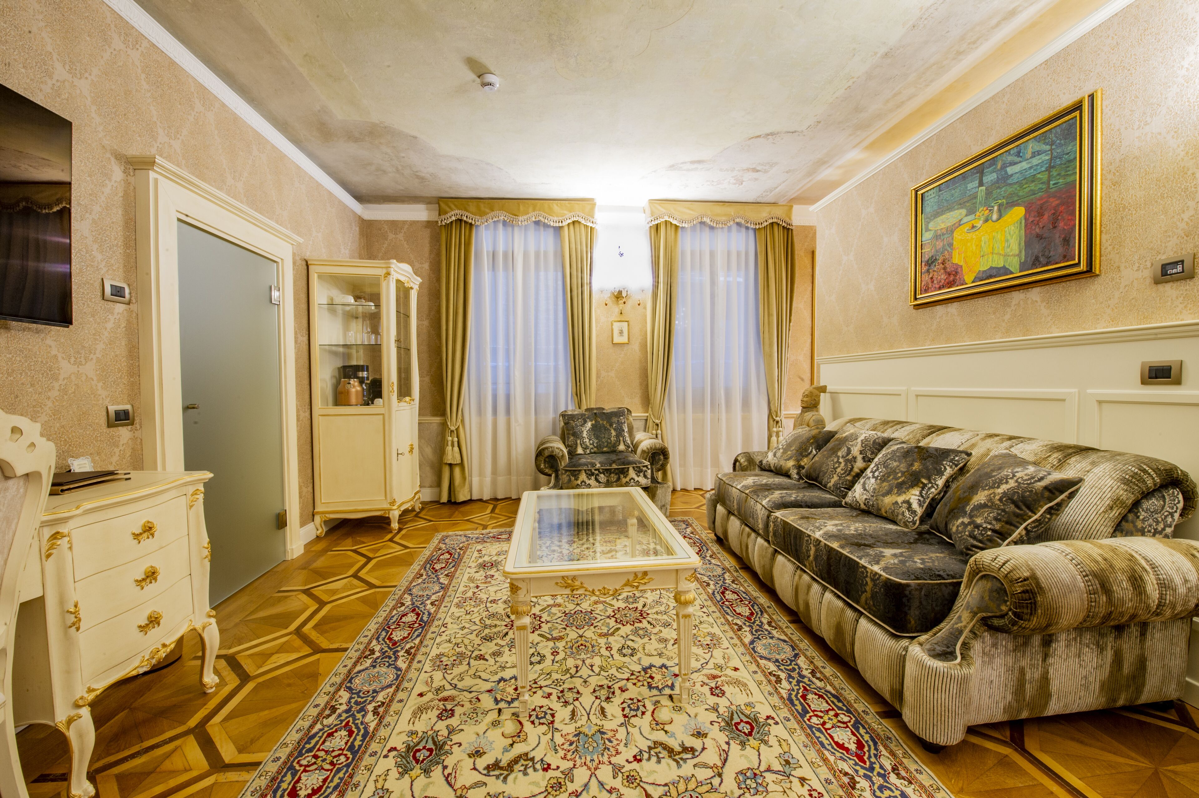 A living room with a sofa, a coffee table, a patterned rug, a cabinet, and curtains.