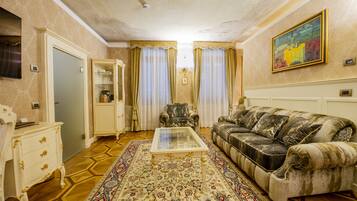 A living room with a sofa, a coffee table, a patterned rug, a cabinet, and curtains.