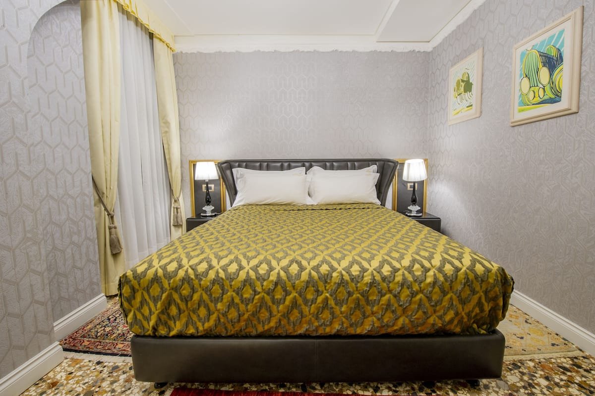 A neatly made bed with a patterned bedspread, two bedside lamps, and a decorative rug.