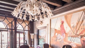 A room with a chandelier, a large painting of a cityscape, and a table with chairs. - EGO’ Boutique Hotel - The Silk Road (Venice)