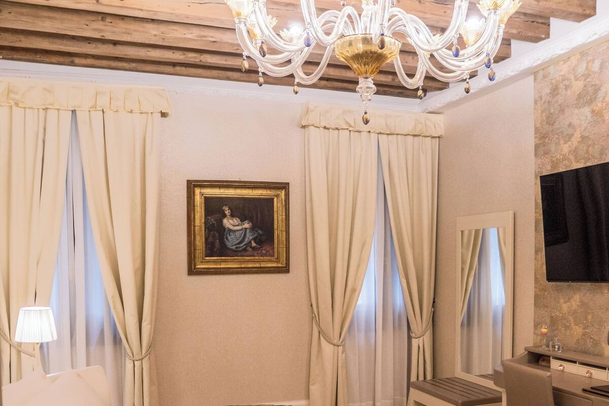Una habitación de hotel con cama redonda, un escritorio, una silla, una araña y un cuadro en la pared.
