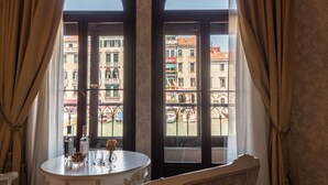 A room with a table and chairs, a window with curtains, and a view of buildings outside. - EGO’ Boutique Hotel - The Silk Road (Venice)