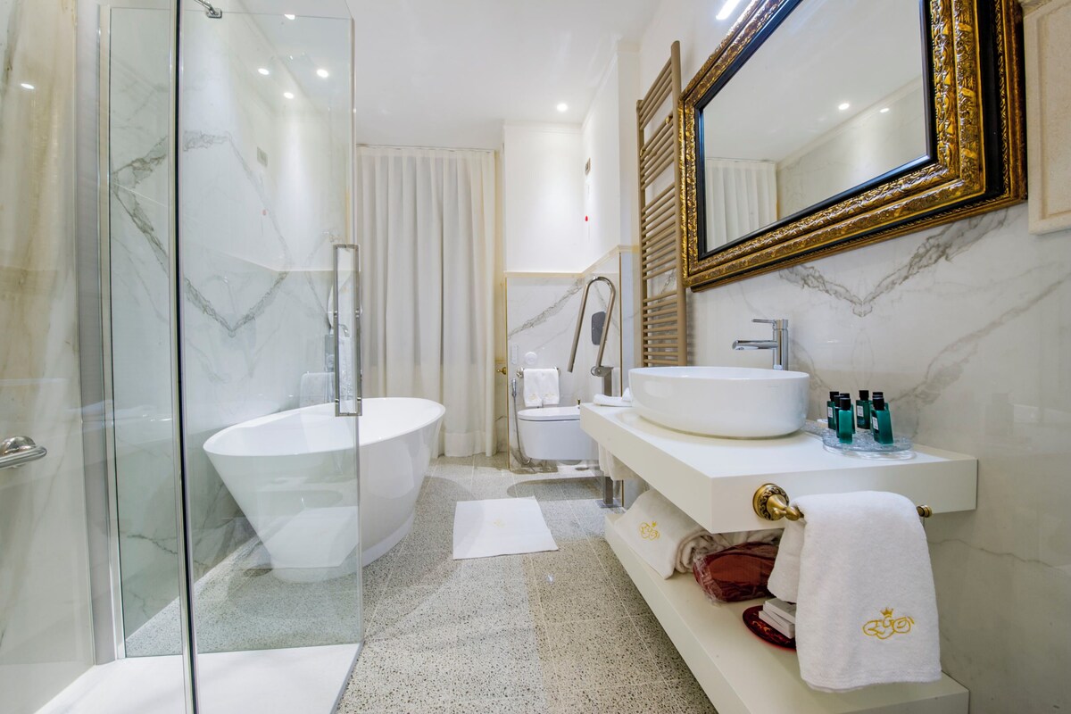 Een moderne badkamer met een glazen douchecabine, een vrijstaand bad, een wastafelmeubel en een grote spiegel.