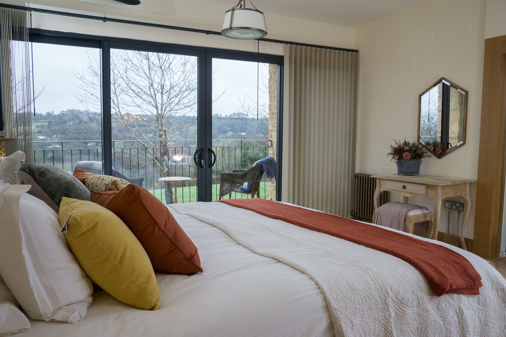 A hotel room with a large bed, a view of the outdoors, and a balcony with a chair.