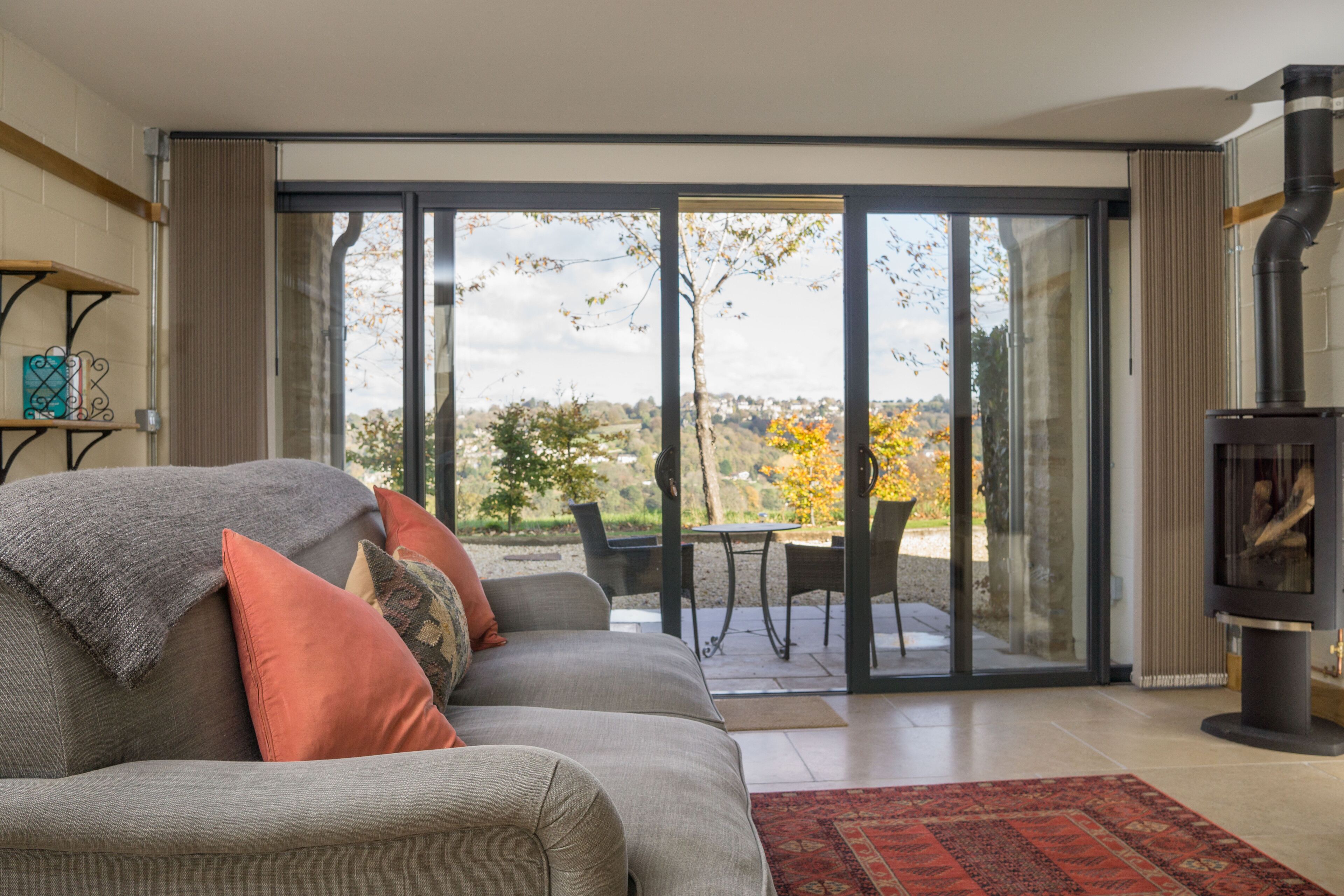 Una sala de estar con sofá, chimenea y puerta corrediza de vidrio que da a un patio exterior.