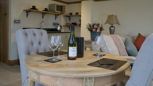 Un coin repas avec une table ronde, deux chaises, une bouteille de vin et deux verres à vin.
