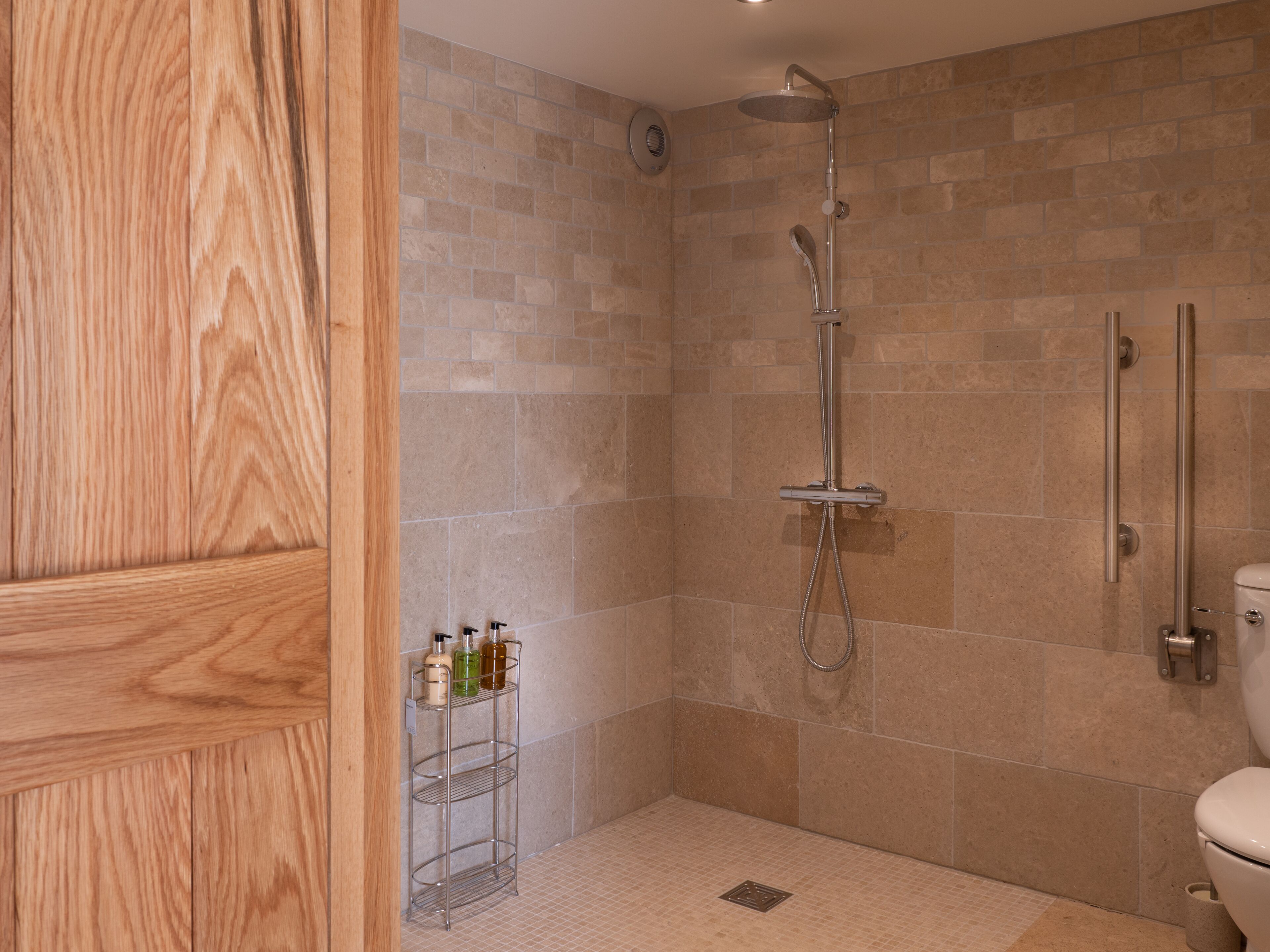 Un baño con ducha, inodoro y puerta de madera.