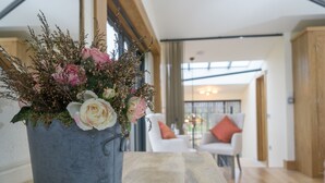 Un salon moderne avec une grande fenêtre, une plante en pot ornée de fleurs et un canapé avec des coussins.