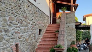 Una escalera de piedra que lleva a un porche de madera con plantas en macetas.