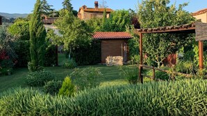 Un jardín bien cuidado con una pérgola de madera, estructuras de piedra y abundante vegetación.