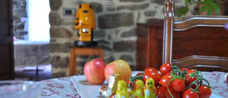 A table with a plate of food, including apples, tomatoes, and wrapped chocolates.
