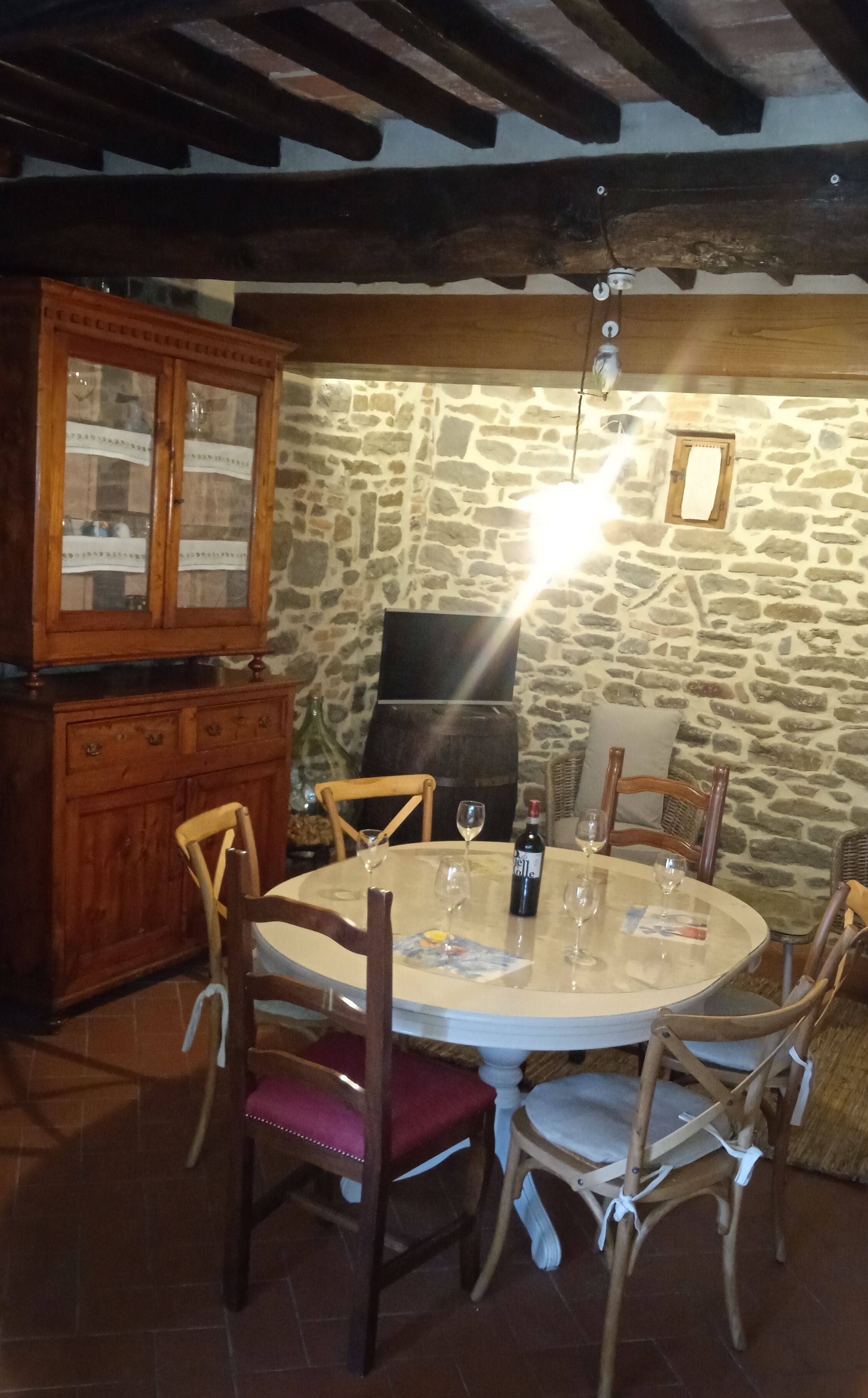 A round dining table with chairs, a wooden cabinet, and a stone wall.