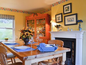 A dining room with a wooden table set for four, a fireplace, and a bookshelf. - 2 bedroom accommodation in Fearnbeg, near Applecross (Fearnbeg, near Applecross)