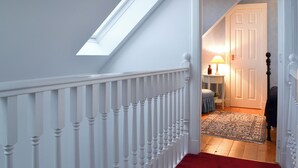 A staircase with a white railing, a skylight, and a red carpet leading to a room with a lamp and a door. - 2 bedroom accommodation in Fearnbeg, near Applecross (Fearnbeg, near Applecross)