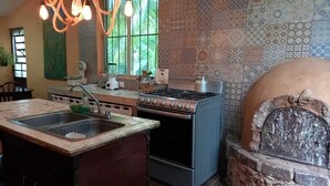 Una cocina con lavaplatos, estufa y horno. Se ve un ventanal con vistas a zonas verdes.