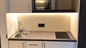 A compact kitchenette with a microwave, sink, and stove. - Heidelberg Hospitality Boarding House (Heidelberg)