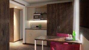A modern kitchen with wooden cabinets, a microwave, and a dining area with a table and chairs. - Heidelberg Hospitality Boarding House (Heidelberg)