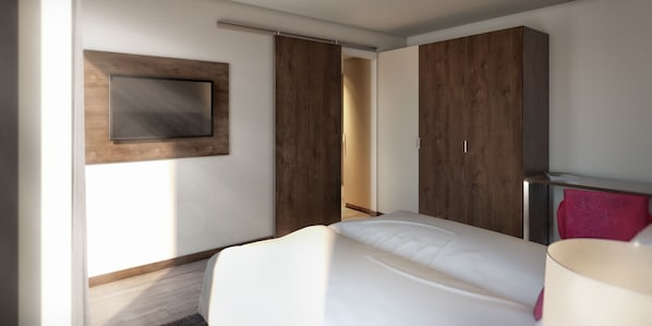 Ein modernes Hotelzimmer mit Bett, Wandfernseher und Kleiderschrank mit Schiebetüren.