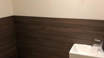A small bathroom with a white toilet, a white sink, and a dark wood vanity.