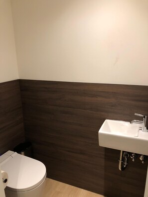 A small bathroom with a white toilet, a white sink, and a dark wood vanity. - Heidelberg Hospitality Boarding House (Heidelberg)
