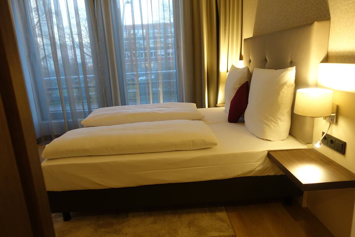 Ein Hotelzimmer mit einem Bett, einem Nachttisch und einem Fenster mit Vorhängen.
