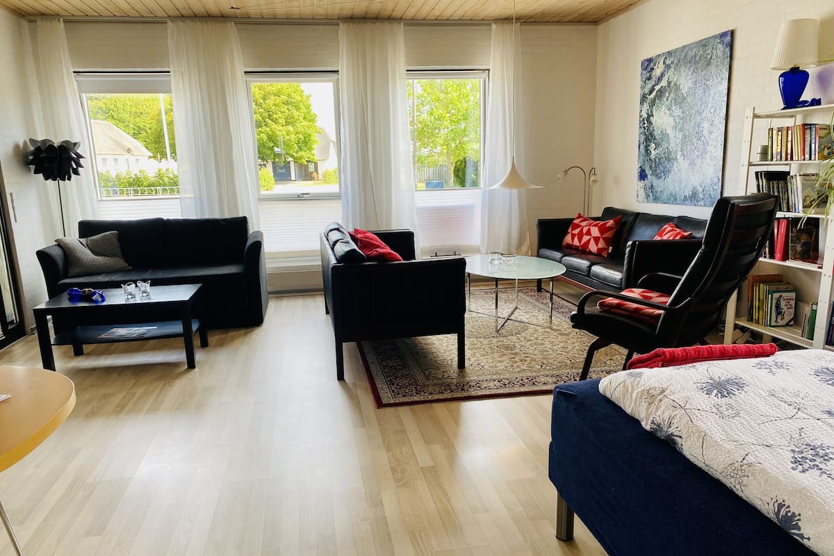 Ein modernes Wohnzimmer mit einer Couch, einem Sessel, einem Couchtisch und einem Bücherregal.
