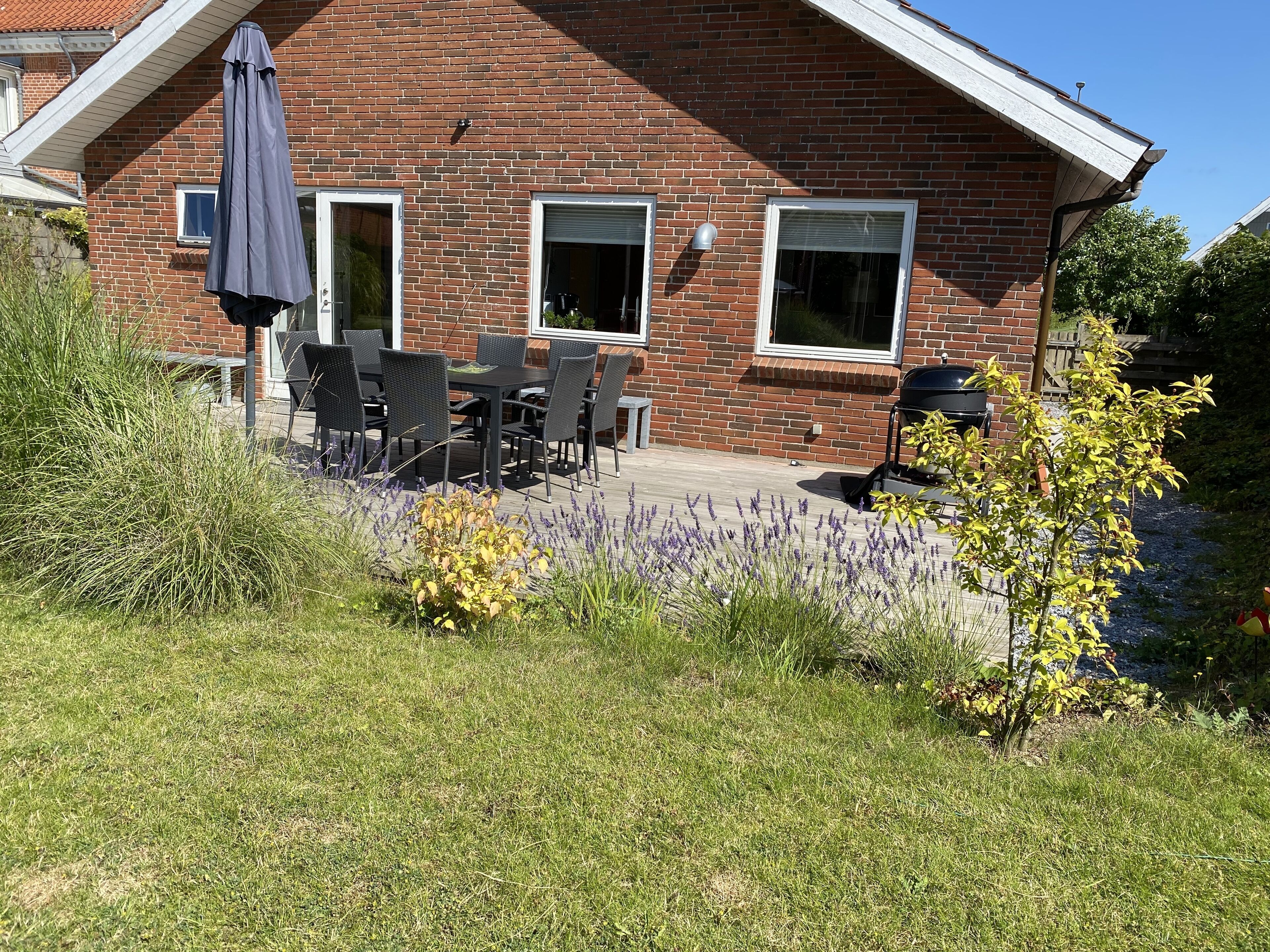 A brick house with a patio, outdoor seating, and a garden with lavender.