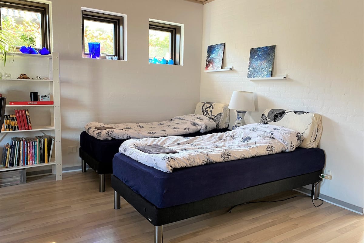 Ein Schlafzimmer mit zwei Betten, einem Bücherregal und Bildern an den Wänden.
