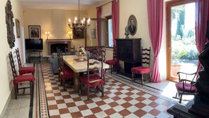 Un comedor con piso a cuadros, una araña, una chimenea y un televisor.