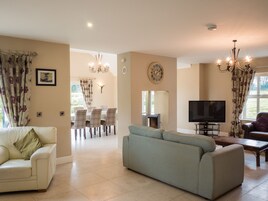 A living room with a sofa, a TV, a fireplace, and a dining area with chairs and a table.