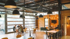 Un intérieur avec des planchers en bois, des tables rondes et des suspensions noires.